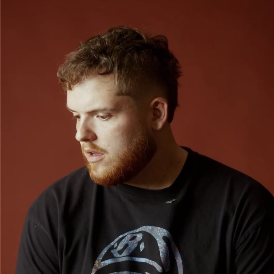 Tanner Castille seated against a rust-red studio backdrop
